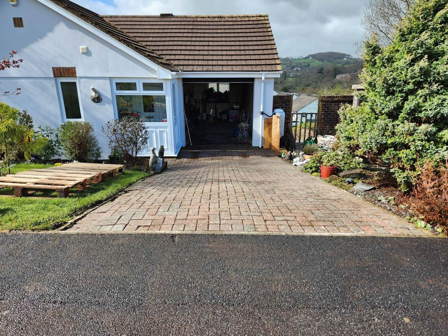 Driveway resurfacing — fresh block paving leading up to a blue bungalow